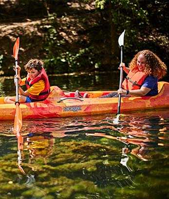 A cub scout and a leader have fun kayaking together