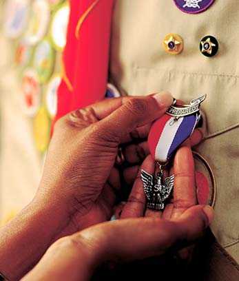 A person cups an Eagle Award pin on a cub scout uniform
